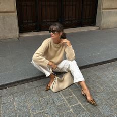 French woman wearing a sweater and white jeans