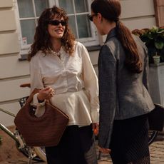 two women looking at each other in stylish clothes