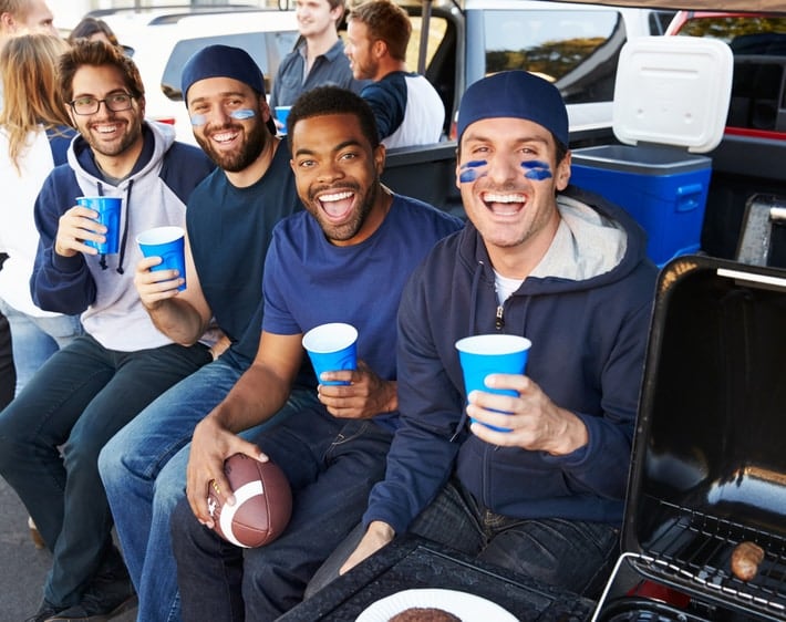Four friends tailgating in the back of a truck