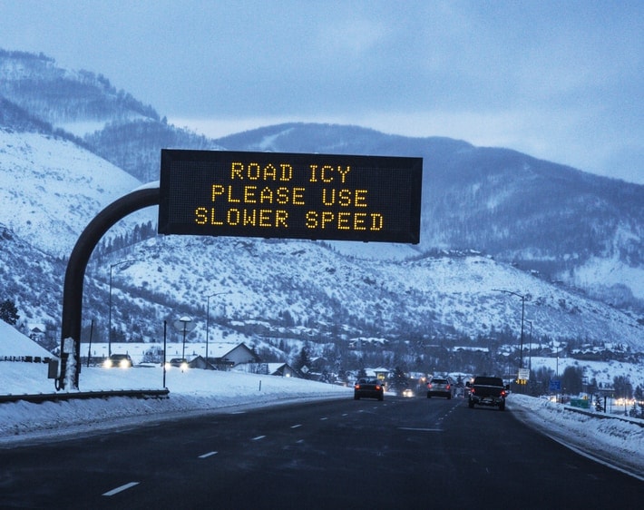 Road icy please use slower speed sign over highway