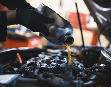 mechanic pouring oil into a car's engine