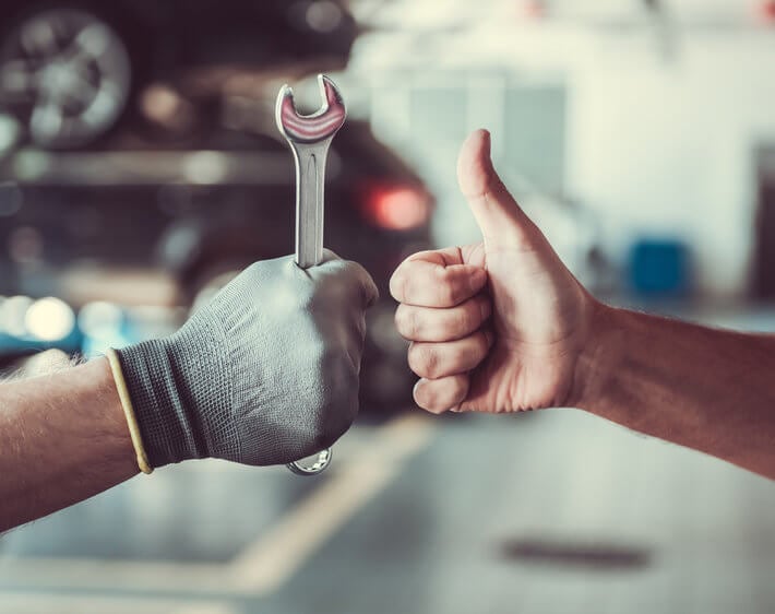 technician holding wrench fist bumping customer