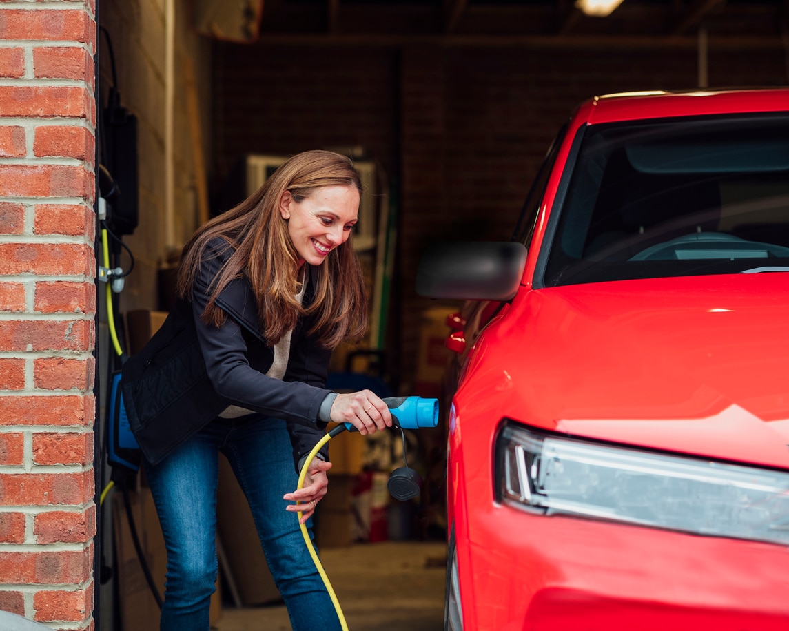 image of a woman plugging in an electric car
